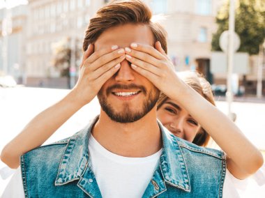 Gülümseyen güzel kız ve onun yakışıklı hipster erkek arkadaşı. Kadın erkek gözlerini elleriyle kapatıyor. Mutlu neşeli bir aile. Dışarıda duran sevgi dolu çifte sarılıyorlar. Bil bakalım kim kavramı 