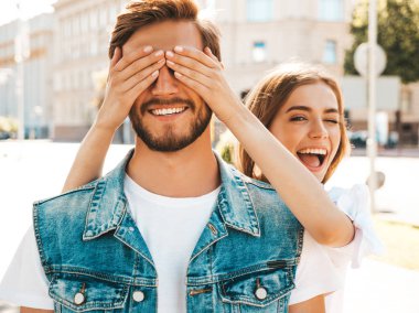 Gülümseyen güzel kız ve onun yakışıklı hipster erkek arkadaşı. Kadın erkek gözlerini elleriyle kapatıyor. Mutlu neşeli bir aile. Dışarıda duran sevgi dolu çifte sarılıyorlar. Bil bakalım kim kavramı 