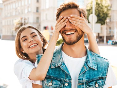 Gülümseyen güzel kız ve onun yakışıklı hipster erkek arkadaşı. Kadın erkek gözlerini elleriyle kapatıyor. Mutlu neşeli bir aile. Dışarıda duran sevgi dolu çifte sarılıyorlar. Bil bakalım kim kavramı 