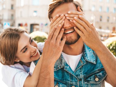 Gülümseyen güzel kız ve onun yakışıklı hipster erkek arkadaşı. Kadın erkek gözlerini elleriyle kapatıyor. Mutlu neşeli bir aile. Dışarıda duran sevgi dolu çifte sarılıyorlar. Bil bakalım kim kavramı 