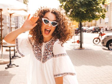 Yaz hipster beyaz elbise giymiş afro bukleler saç modeli ile güzel gülümseyen model. Seksi kaygısız kız sokakta poz. Trendy komik ve pozitif kadın güneş gözlüğü eğlenmek