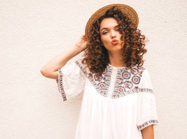 Yaz hipster beyaz elbise giymiş afro bukleler saç modeli ile güzel gülümseyen model. Seksi kaygısız kız şapka beyaz duvar yakınında sokakta poz. Komik, pozitif kadın eğleniyor ve delioluyor