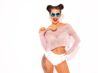 Güneş gözlüğü kırmızı dudaklar ile Genç güzel seksi hipster kadın. Yaz mayo giysileri trendy kız. Pozitif kadın deliriyordu. Komik model beyaz izole. İki boynuz. Şeker lolipop yeme