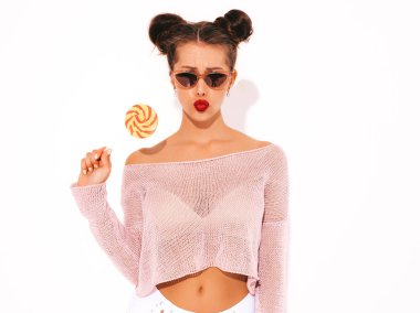 Güneş gözlüğü kırmızı dudaklar ile Genç güzel seksi hipster kadın. Yaz mayo giysileri trendy kız. Pozitif kadın deliriyordu. Komik model beyaz izole. İki boynuz. Şeker lolipop yeme