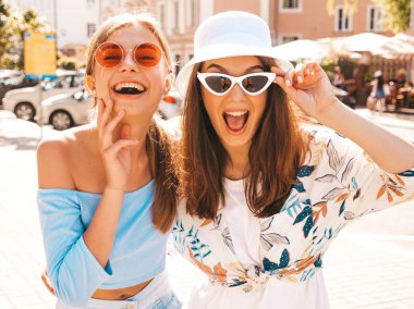 Trendy yazlık giysiler ve panama şapka iki genç güzel gülümseyen hipster kız. Seksi kaygısız kadınlar sokak arka planda poz. Güneş gözlüğü ile eğlenen pozitif modeller. Sarılma