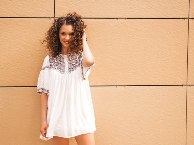 Yaz hipster beyaz elbise giymiş afro bukleler saç modeli ile güzel gülümseyen model. Seksi kaygısız kız sarı duvara yakın sokakta poz. Komik ve pozitif kadın eğleniyor