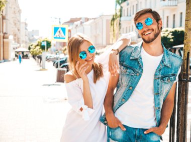 Gülümseyen güzel kız ve onun yakışıklı erkek arkadaşı sokakta yürüyor. Rahat yazlık elbiseli kadın ve kot pantolon giyen bir erkek. Mutlu neşeli çift aile güneş gözlüğü eğlenmek