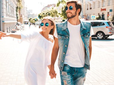 Gülümseyen güzel kız ve onun yakışıklı erkek arkadaşı sokakta yürüyor. Rahat yazlık elbiseli kadın ve kot pantolon giymiş bir erkek. Güneş gözlüğü ile mutlu neşeli aile. Gösterir ve ilginç bir şey işaret