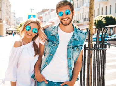 Gülümseyen güzel kız ve onun yakışıklı erkek arkadaşı sokakta yürüyor. Rahat yazlık elbiseli kadın ve kot pantolon giyen bir erkek. Mutlu neşeli çift aile güneş gözlüğü eğlenmek