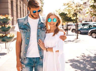 Gülümseyen güzel kız ve onun yakışıklı erkek arkadaşı sokakta yürüyor. Rahat yazlık elbiseli kadın ve kot pantolon giyen bir erkek. Mutlu neşeli çift aile güneş gözlüğü eğlenmek