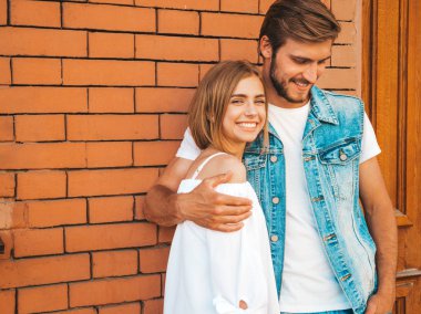 Gülümseyen güzel kız ve onun yakışıklı erkek arkadaşı. Rahat yazlık elbiseli kadın. Kot pantolon giyen adam. Mutlu neşeli bir aile. Kadın tuğla duvara yakın sokakta eğleniyor. Sarılan çift