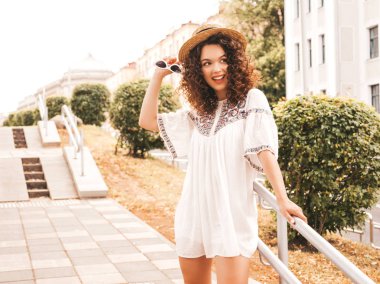 Yaz hipster beyaz elbise giymiş afro bukleler saç modeli ile güzel gülümseyen model portresi. Seksi kaygısız kız sokak arka planda poz. Şapka trendy komik ve pozitif kadın