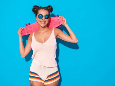 Güneş gözlüğü genç güzel seksi gülümseyen hipster kadın. Yaz aylarında trendy kız örgü hırka konu, şort. Pozitif kadın pembe kuruş kaykay ile deli gidiyor, izole