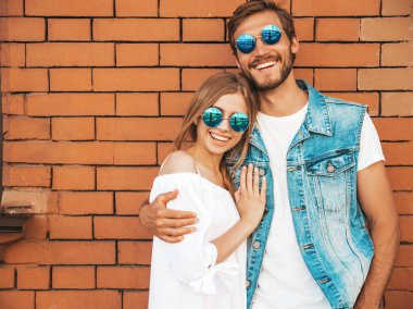 Gülümseyen güzel kız ve onun yakışıklı erkek arkadaşı. Rahat yazlık elbiseli kadın. Kot pantolon giyen adam. Mutlu neşeli bir aile. Kadın tuğla duvara yakın sokakta eğleniyor. Sarılan çift