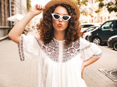 Yaz hipster beyaz elbise giymiş afro bukleler saç modeli ile güzel gülümseyen model. Seksi kaygısız kız sokakta poz. Trendy ve pozitif kadın güneş gözlüğü eğlenmek. Ördek surat yapar