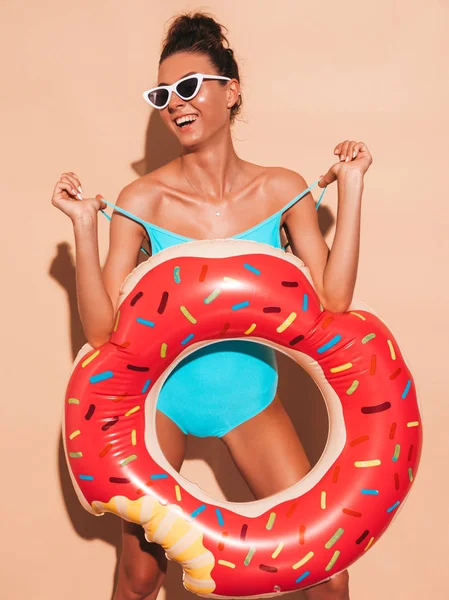 Güneş gözlüğü genç güzel seksi gülümseyen hipster kadın. Donut lilo şişme yatak ile yaz mayo mayo Kız. Pozitif kadın deliriyordu. Şeffaf vizör kapağı bej duvar ayakın
