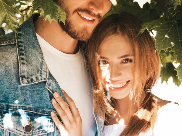 Gülümseyen güzel kız ve onun yakışıklı erkek arkadaşı ağacın yanında sokakta poz. Rahat yazlık elbiseli kadın ve kot pantolon giyen bir erkek. Mutlu neşeli çift aile eğleniyor