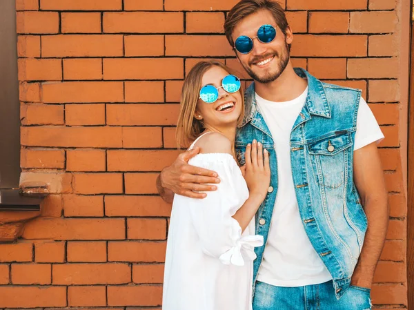 Gülümseyen güzel kız ve onun yakışıklı erkek arkadaşı. Rahat yazlık elbiseli kadın. Kot pantolon giyen adam. Mutlu neşeli bir aile. Kadın tuğla duvara yakın sokakta eğleniyor. Sarılan çift