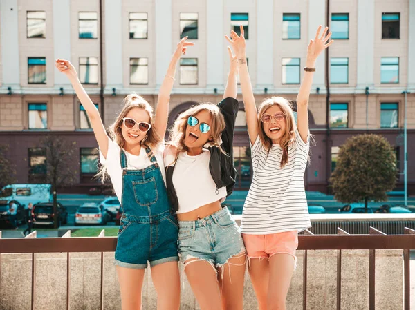 トレンディな夏の服を着た3人の若い美しい笑顔のヒップスターの女の子の肖像画 ストリートの背景にポーズセクシーな気楽な女性 サングラスで楽しいポジティブなモデル 手を上げる — ストック写真
