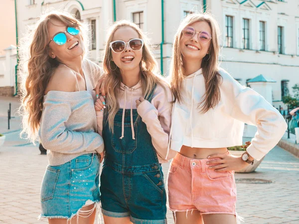 トレンディな夏の服を着た3人の若い美しい笑顔のヒップスターの女の子の肖像画 ストリートの背景にポーズセクシーな気楽な女性 サングラスで楽しいポジティブなモデル 日没時の抱擁 — ストック写真