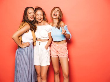 Moda yazlık giysiler üç genç güzel gülümseyen hipster kız. Seksi kaygısız kadınlar stüdyoda pembe duvar yakınında poz. Pozitif modeller deli gidiyor ve eğlenmek