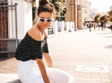 Zarif yazlık giysiler giymiş güzel gülümseyen model. Sokak arka planda oturan seksi kaygısız kız. Güneş gözlüğü trendy modern iş kadını eğlenmek