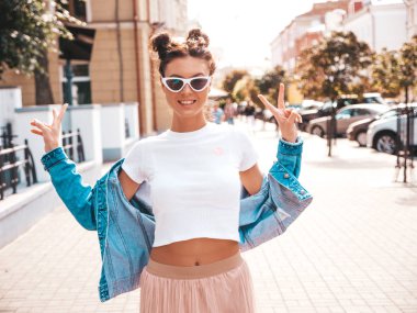 Boynuzları saç modeli yaz hipster ceket kot elbise giymiş güzel gülümseyen model. Seksi kaygısız kız sokak arka planda poz. Trendy komik ve pozitif kadın güneş gözlüğü eğlenmek