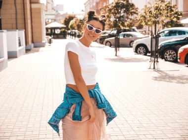 Boynuzları saç modeli yaz hipster ceket kot elbise giymiş güzel gülümseyen model. Seksi kaygısız kız sokak arka planda poz. Trendy komik ve pozitif kadın güneş gözlüğü eğlenmek