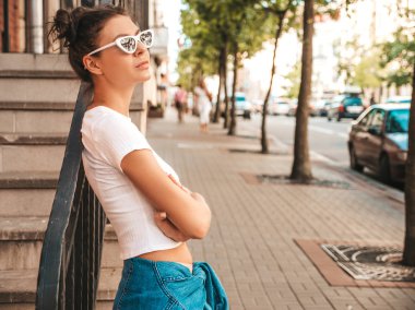 Boynuzları saç modeli yaz hipster ceket kot elbise giymiş güzel gülümseyen model. Seksi kaygısız kız sokak arka planda poz. Trendy komik ve pozitif kadın güneş gözlüğü eğlenmek