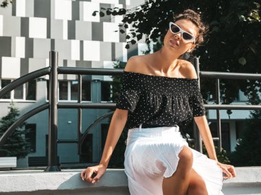 Zarif yazlık giysiler giymiş güzel gülümseyen model. Sokak arka planda oturan seksi kaygısız kız. Güneş gözlüğü trendy modern iş kadını eğlenmek