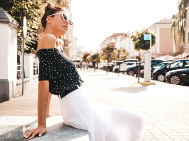 Zarif yazlık giysiler giymiş güzel gülümseyen model. Sokak arka planda oturan seksi kaygısız kız. Güneş gözlüğü trendy modern iş kadını eğlenmek