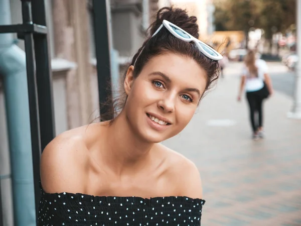 Beautiful smiling model in summer hipster clothes.Sexy carefree girl posing in the street background.Trendy funny and positive woman having fun in sunglasses