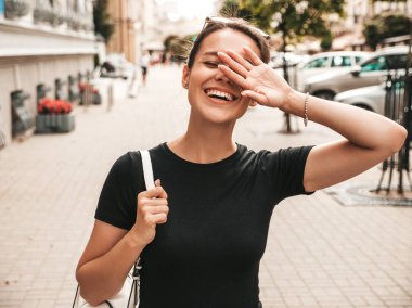 Yaz giysileri giymiş güzel gülümseyen hipster modeli portresi. Sokak arka planda poz veren modaya uygun bir kız. Komik ve pozitif kadın eğleniyor