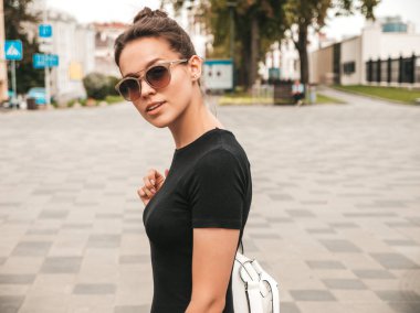 Yaz giysileri giymiş güzel gülümseyen hipster modeli portresi. Modaya uygun kız, sokak arka planında güneş gözlüklüğüyle poz vermek. Komik ve pozitif kadın eğleniyor