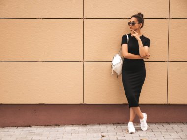 Yaz giysileri giymiş güzel gülümseyen hipster modeli portresi. Sokak arka planda poz veren modaya uygun bir kız. Komik ve pozitif kadın güneş gözlüğü eğlenmek