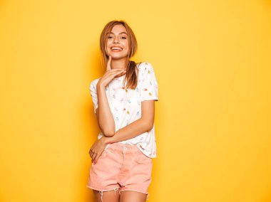 Moda yazlık kot şort giysiler genç güzel gülümseyen hipster kız Portresi. Seksi kaygısız kadın stüdyoda sarı duvar yakınında poz. Olumlu model eğlenmek 
