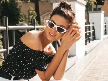 Zarif yazlık giysiler giymiş güzel gülümseyen model. Sokak arka planda oturan seksi kaygısız kız. Güneş gözlüğü trendy modern iş kadını eğlenmek