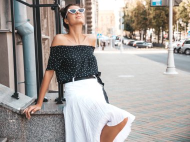 Zarif yazlık giysiler giymiş güzel gülümseyen model. Sokak arka planda oturan seksi kaygısız kız. Güneş gözlüğü trendy modern iş kadını eğlenmek