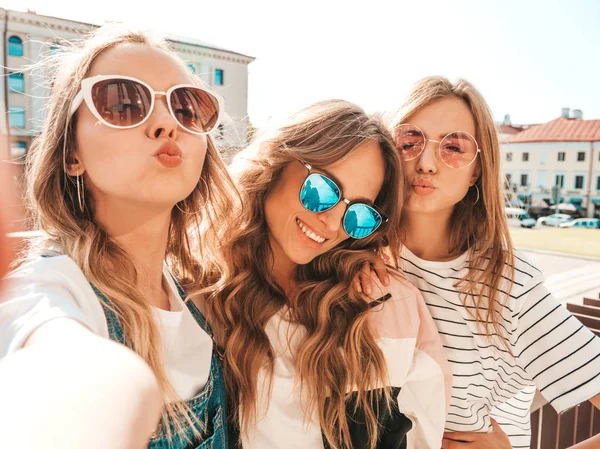 夏服を着た3人の若い笑顔のヒップスター女性 スマートフォンで自分撮りセルフポートレート写真を撮る女の子 路上でポーズをとるモデル サングラスでポジティブな顔の感情を示す女性 — ストック写真
