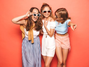 Moda yazlık giysiler üç genç güzel gülümseyen hipster kız. Seksi kaygısız kadınlar stüdyoda sarı duvar yakınında poz. Pozitif modeller deli gidiyor ve güneş gözlüğü eğlenmek