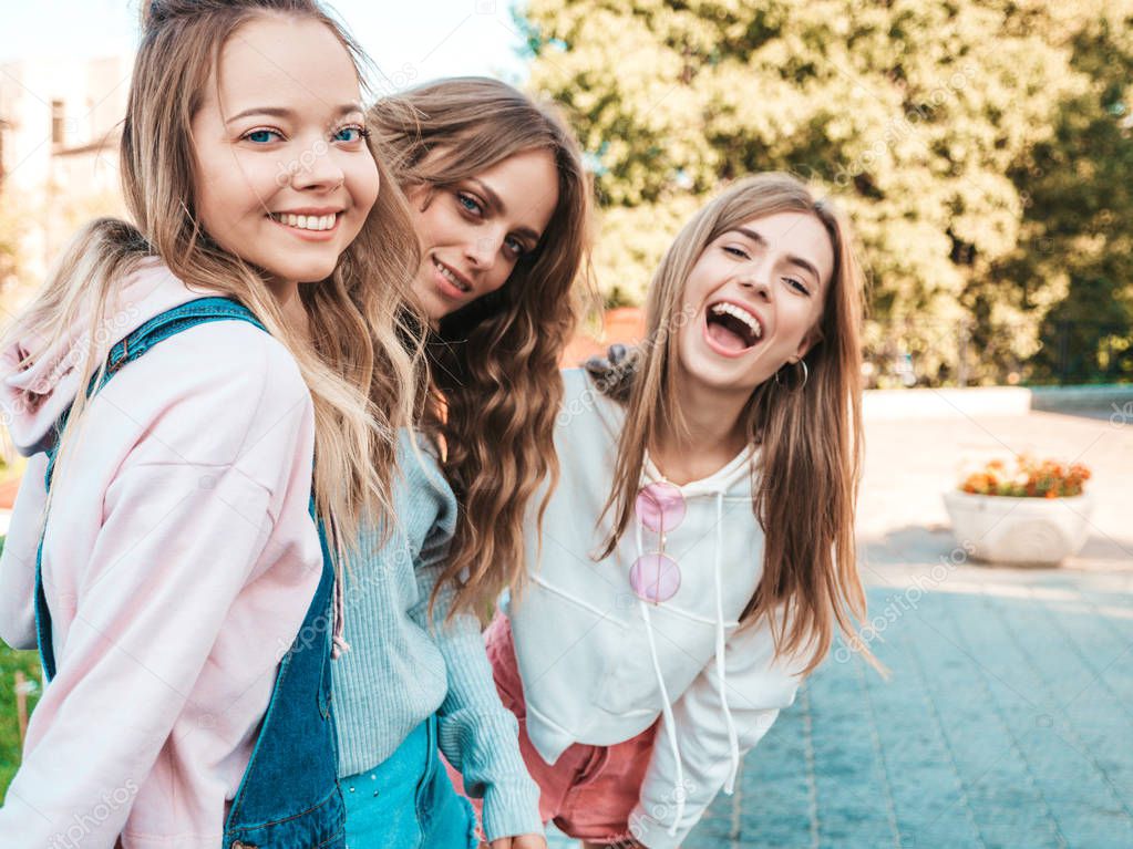 Portrait of three young beautiful smiling hipster girls in trendy summer clothes. Sexy carefree women posing on the street background.Positive models having fun in sunglasses.Hugging