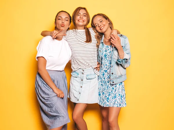 トレンディな夏の服を着た3人の若い美しい笑顔のヒップスターの女の子 スタジオで黄色い壁の近くでポーズをとるセクシーな気楽な女性 ポジティブなモデルはクレイジーに行くと楽しみを持っています — ストック写真