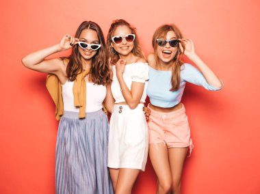 Moda yazlık giysiler üç genç güzel gülümseyen hipster kız. Seksi kaygısız kadınlar stüdyoda sarı duvar yakınında poz. Pozitif modeller deli gidiyor ve eğlenmek 