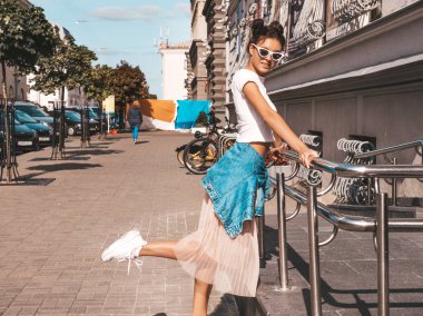 Boynuzları saç modeli yaz hipster ceket kot elbise giymiş güzel gülümseyen model. Seksi kaygısız kız sokak arka planda poz. Trendy komik ve pozitif kadın güneş gözlüğü eğlenmek