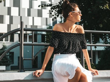 Zarif yazlık giysiler giymiş güzel gülümseyen model. Sokak arka planda oturan seksi kaygısız kız. Güneş gözlüğü trendy modern iş kadını eğlenmek