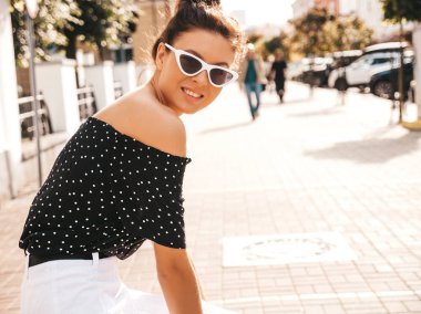 Zarif yazlık giysiler giymiş güzel gülümseyen model. Sokak arka planda oturan seksi kaygısız kız. Güneş gözlüğü trendy modern iş kadını eğlenmek