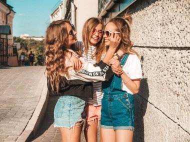 Moda yazlık giysiler üç genç güzel gülümseyen hipster kız Portresi. Sokakta duvara yakın poz seksi kaygısız kadınlar. Güneş gözlüğü ile eğlenen pozitif modeller