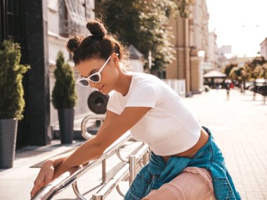 Boynuzları saç modeli yaz hipster ceket kot elbise giymiş güzel gülümseyen model. Seksi kaygısız kız sokak arka planda poz. Trendy komik ve pozitif kadın güneş gözlüğü eğlenmek