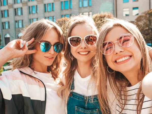 夏服を着た3人の若い笑顔のヒップスター女性 スマートフォンで自分撮りセルフポートレート写真を撮る女の子 路上でポーズをとるモデル 肯定的な顔の感情を示す女性 — ストック写真