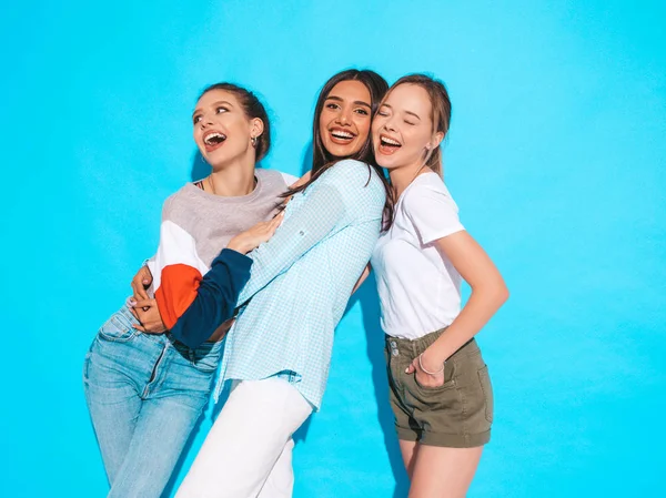 流行の夏服の3人の若い美しい笑顔ヒップスターの女の子 スタジオの青い壁の近くにポーズをとるセクシーな屈託のない女性 楽しさと抱擁を持つ肯定的なモデル — ストック写真